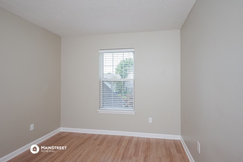 the living room of an apartment with wood floors and a window