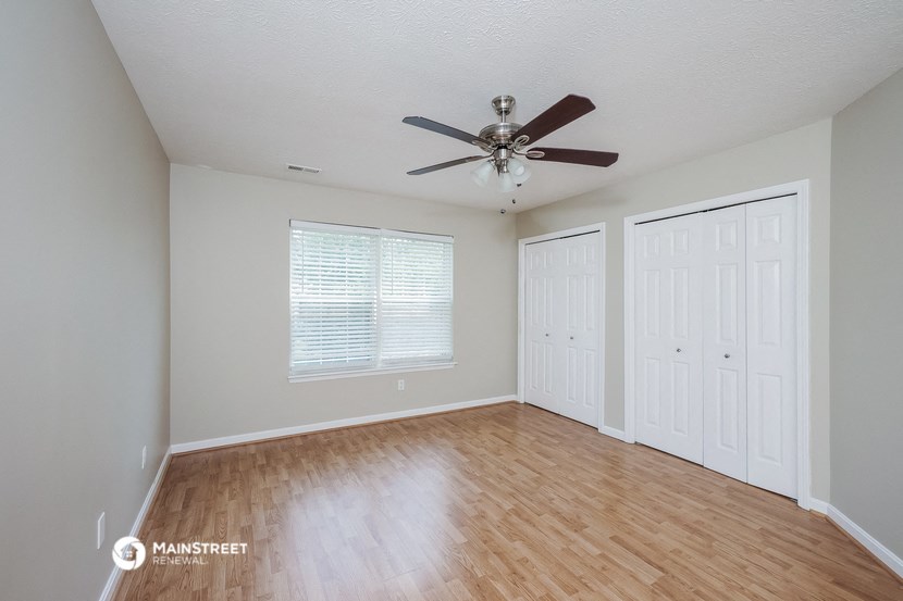an empty living room with a ceiling fan and a closet