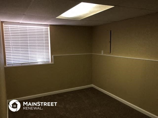 a small room with a window and a brown carpet