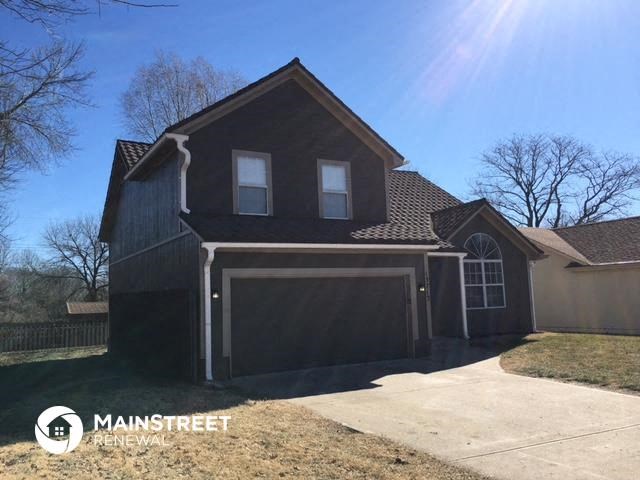 a black house with a driveway and a garage