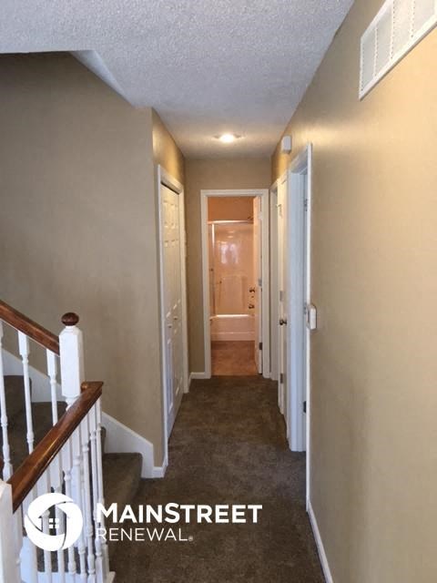 a hallway of a house with a staircase and a white door