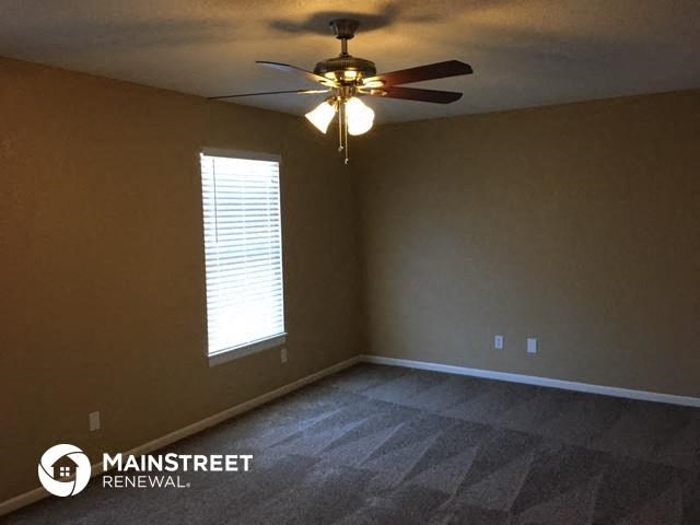 an empty room with a ceiling fan and a window