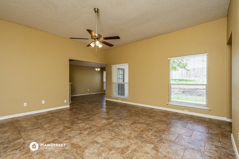 an empty living room with a ceiling fan and a window