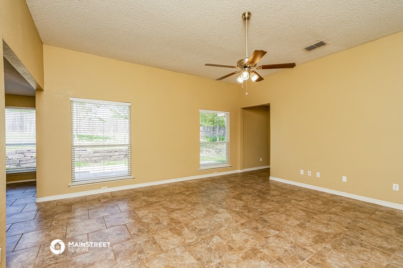 an empty living room with a ceiling fan