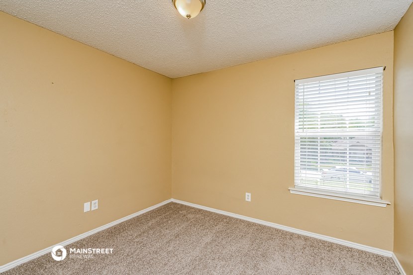 an empty bedroom with a large window and carpeting