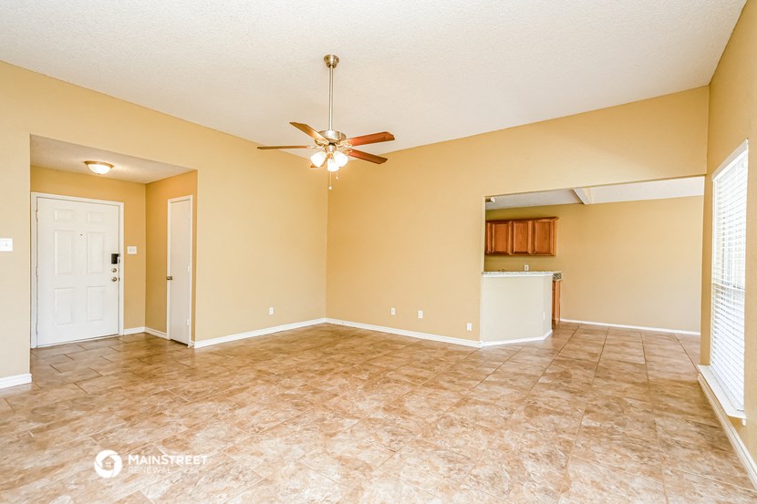 an empty living room with a ceiling fan