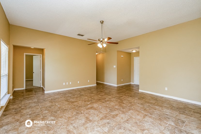 an empty living room with a ceiling fan