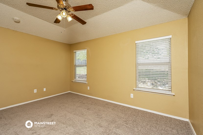 an empty room with a ceiling fan and a window