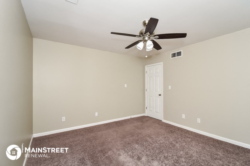 the spacious living room with carpet and ceiling fan