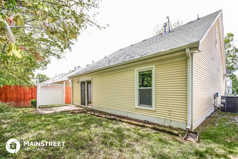 a small yellow house with a yard and a garage