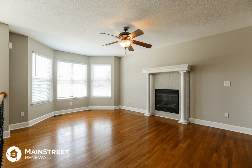 a living room with a ceiling fan and a fireplace
