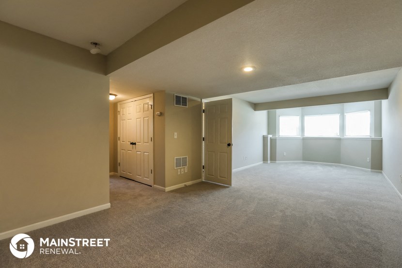 the upstairs living room of an apartment with carpet and a door to a closet