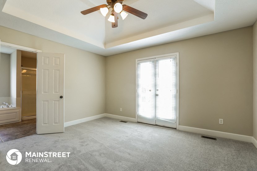 an empty room with a ceiling fan and a door to a bathroom