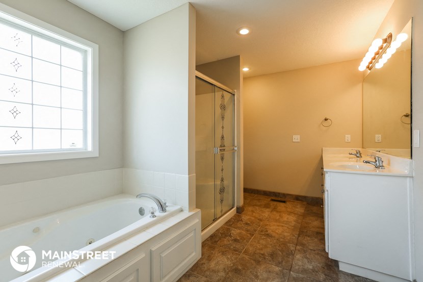 the master bathroom has a large tub and a shower