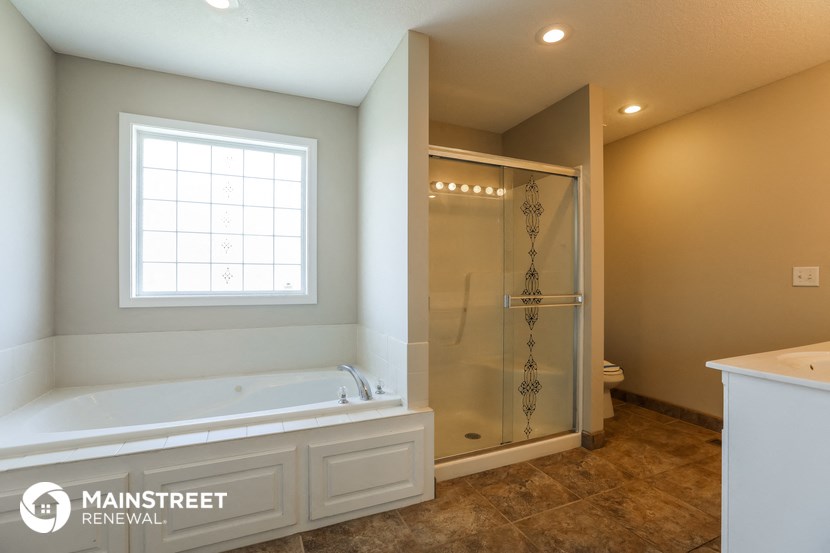 the master bathroom has a large tub and a shower