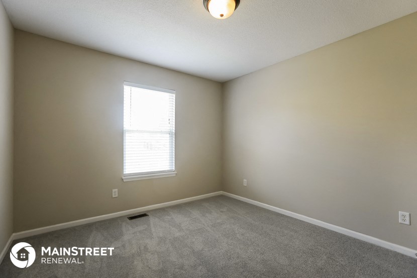 the upstairs bedroom has a carpeted floor and a window
