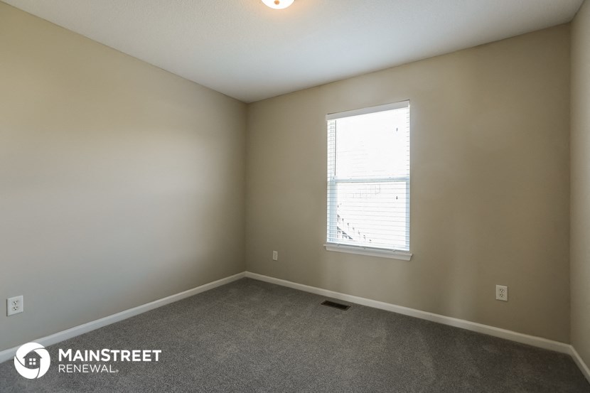 a bedroom with a window and a carpeted floor