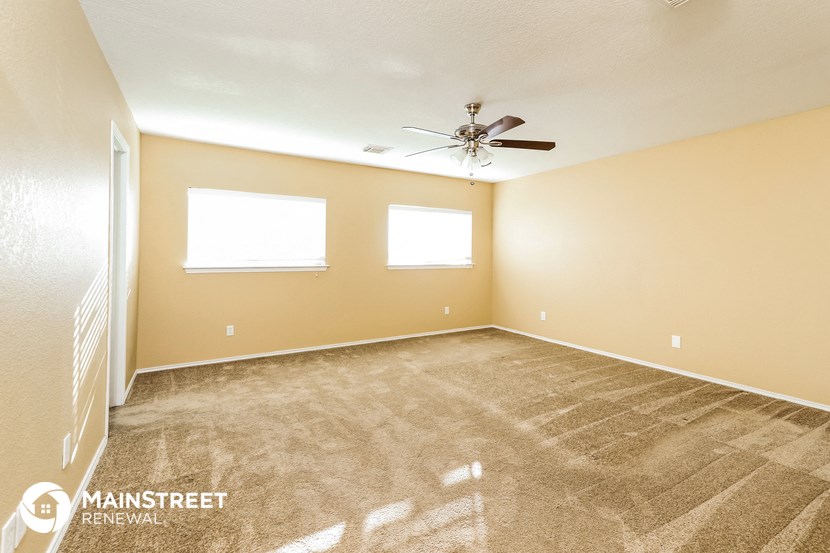 the spacious living room with carpeting and a ceiling fan