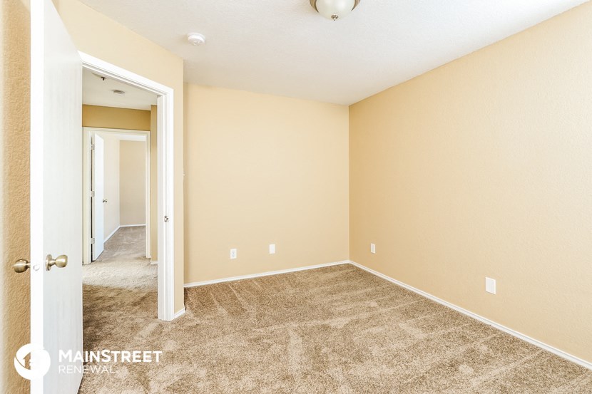 an empty living room with carpet and a door to a hallway