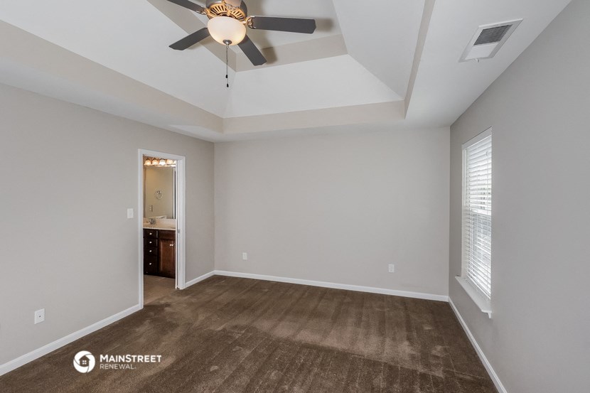 an empty living room with a ceiling fan and a carpet