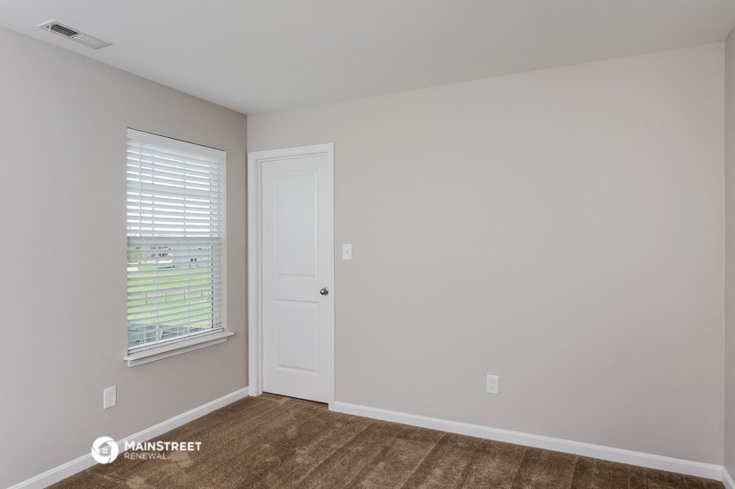 the living room of an apartment with a door and a window
