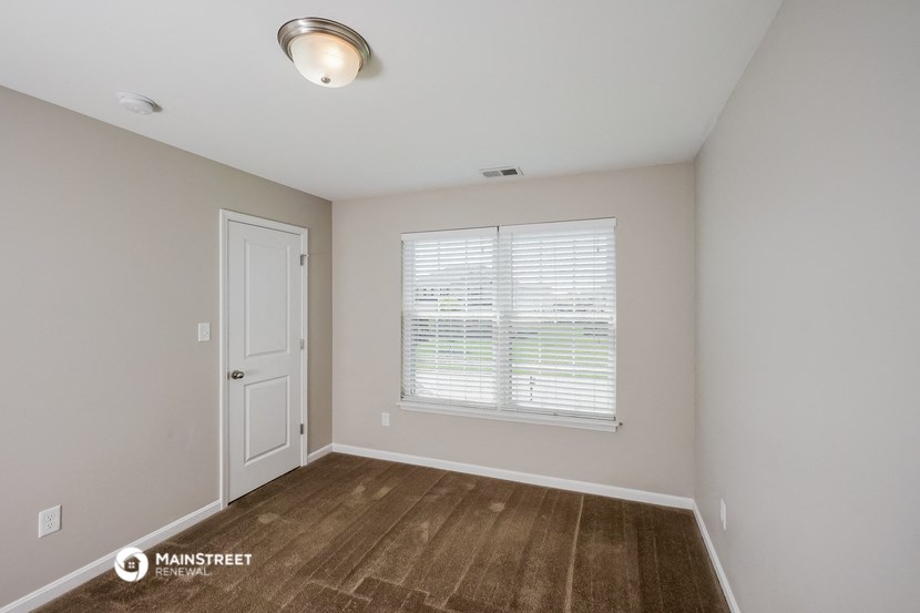 the spacious living room with a large window and wood flooring