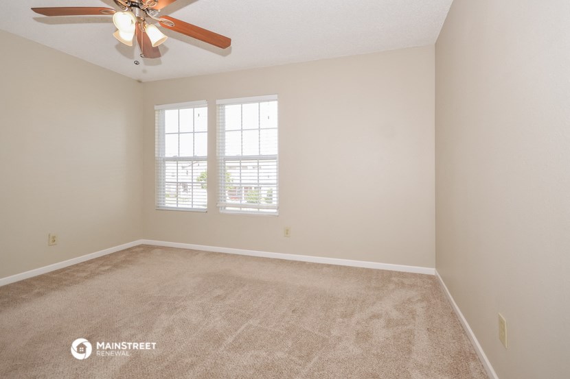 an empty room with a ceiling fan and a window