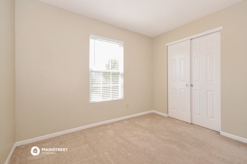 a bedroom with a door and a window and a carpeted floor