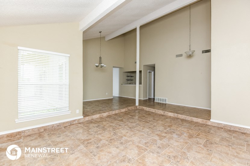 an empty living room with a large window and tile floor