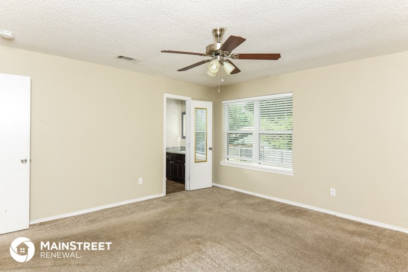 an empty living room with a ceiling fan and a window