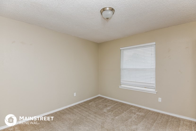 the bedroom of this home has a carpeted floor and a window