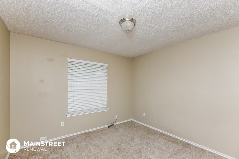 the spacious bedroom of this manufactured home has carpeted flooring and a large window