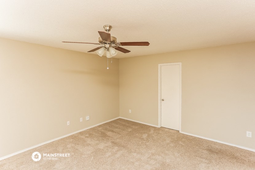 an empty living room with a ceiling fan