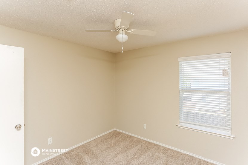 an empty bedroom with a ceiling fan and a window