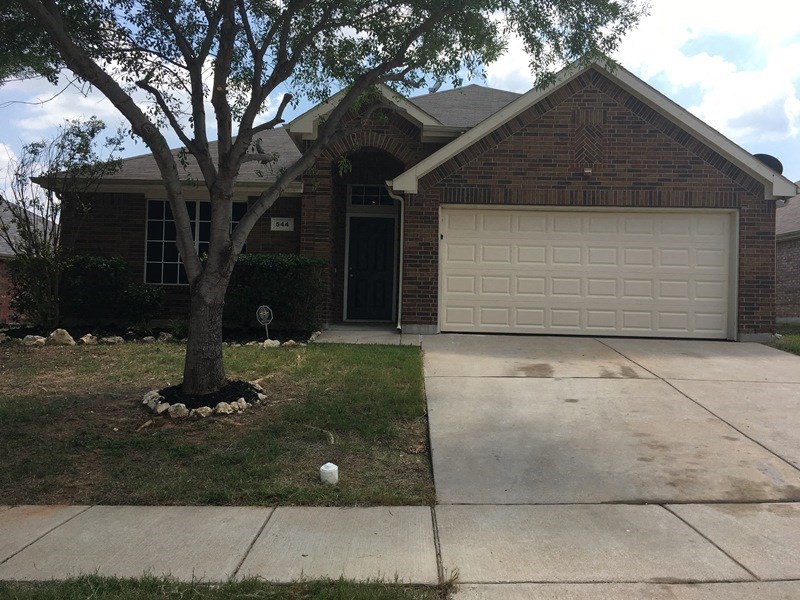 a house with a driveway and a tree in front of it