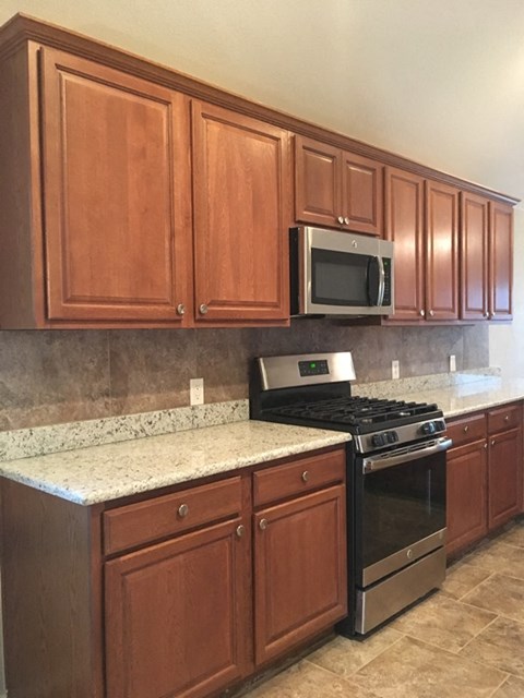 a kitchen with wooden cabinets and a stove and a microwave