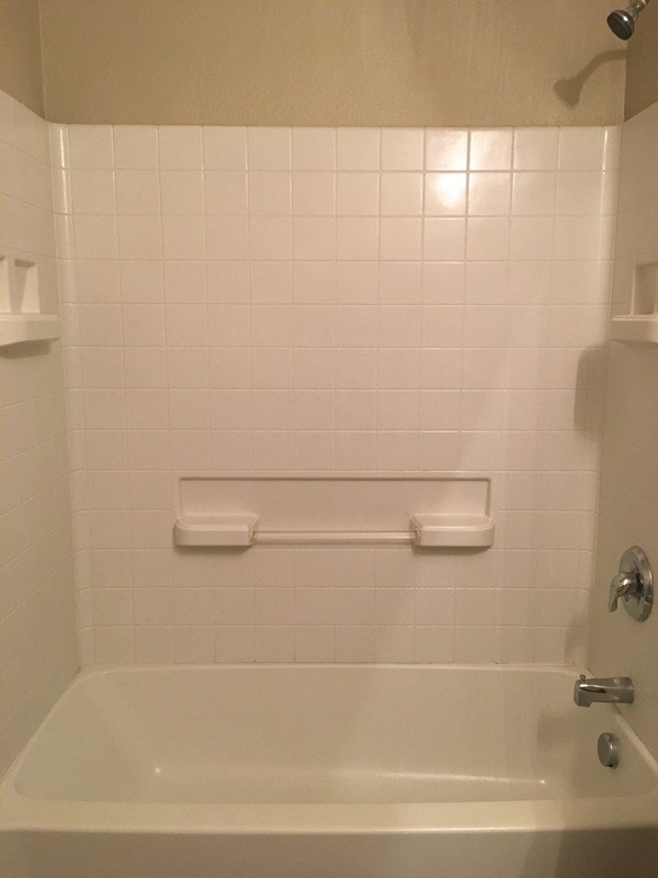 a white bath tub in a bathroom with a towel rack on the side