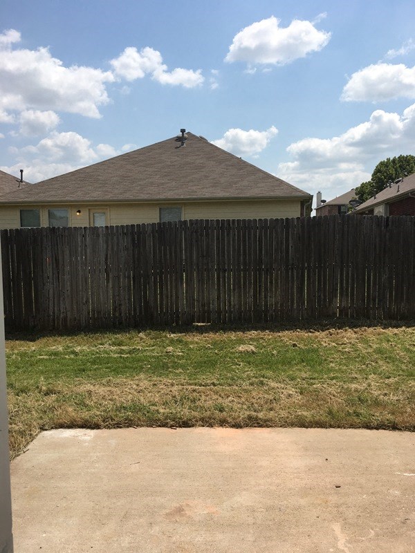 a backyard with a wooden fence and a house behind it