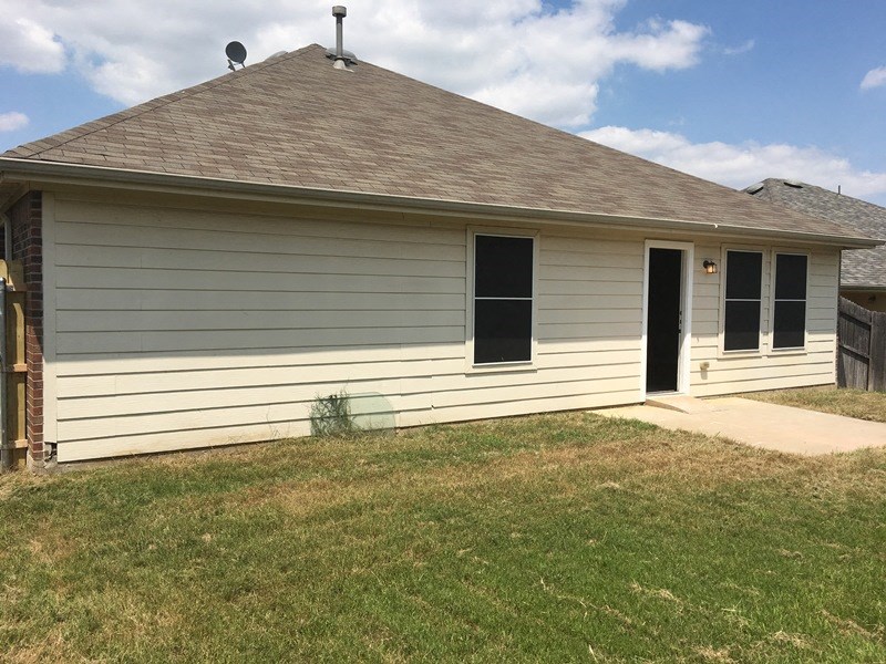 the front of a white house with a yard and a driveway
