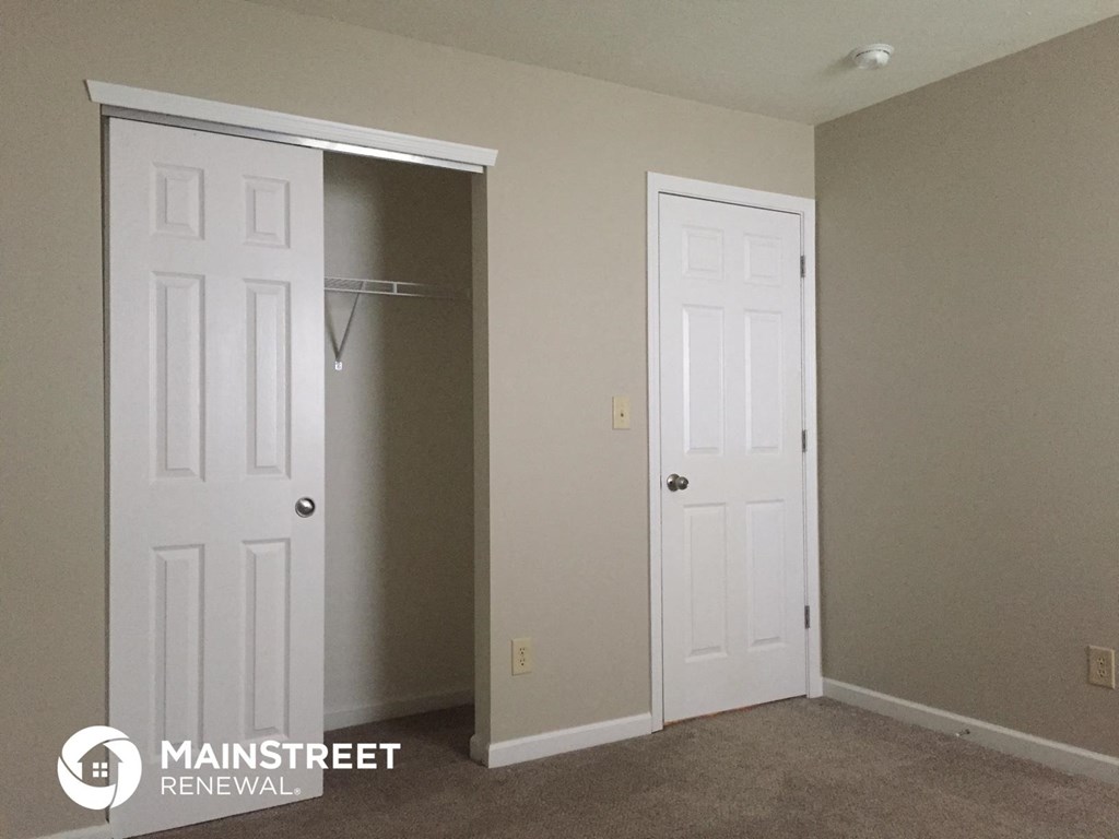 a room with a closet and a closet door and a white door to a bathroom