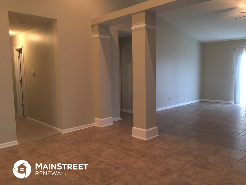 an empty living room with pillars and a tile floor