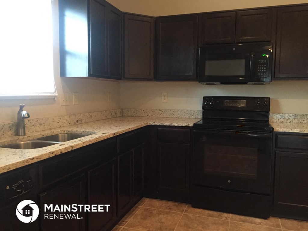 a kitchen with black cabinets and a black stove and a sink