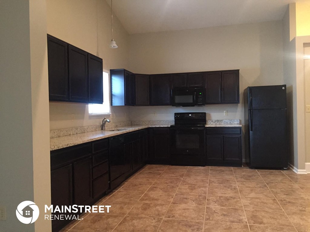 an empty kitchen with black cabinets and black appliances