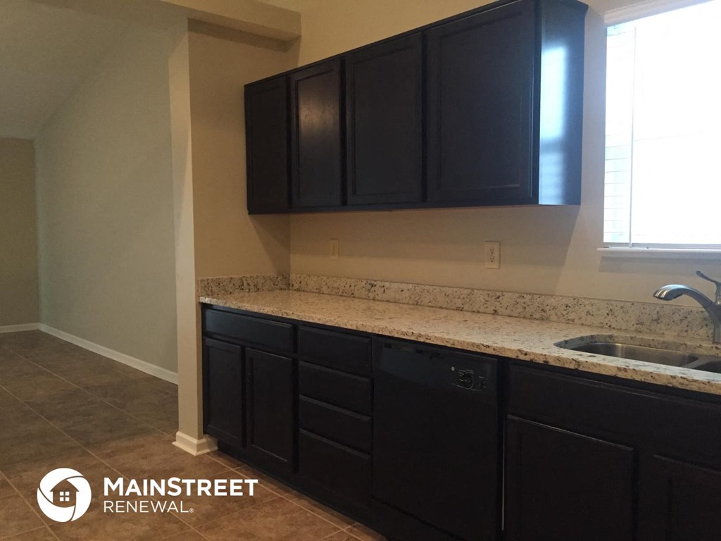 a kitchen with black cabinets and a counter top and a sink