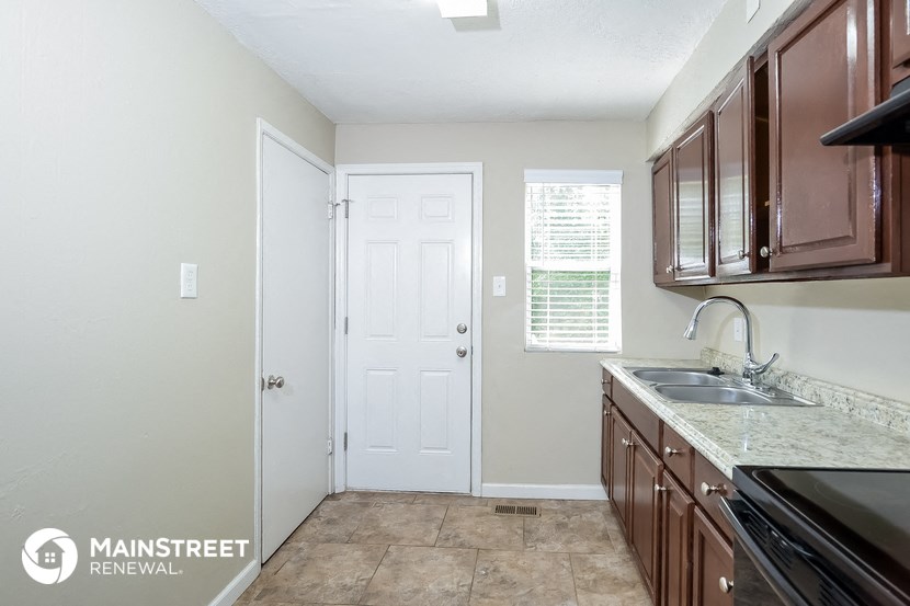 a kitchen with brown cabinets and a sink and a white door