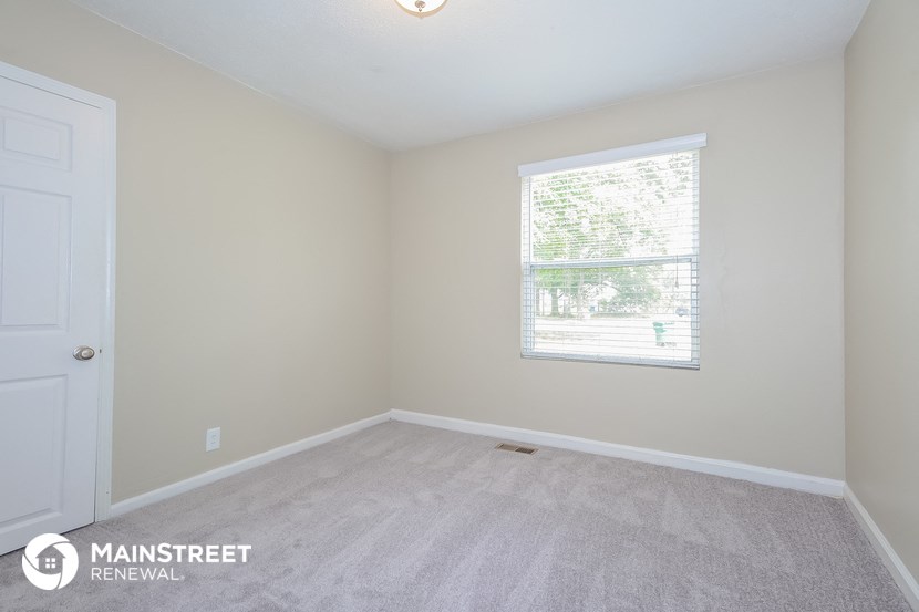 the upstairs bedroom with carpeted flooring and a window