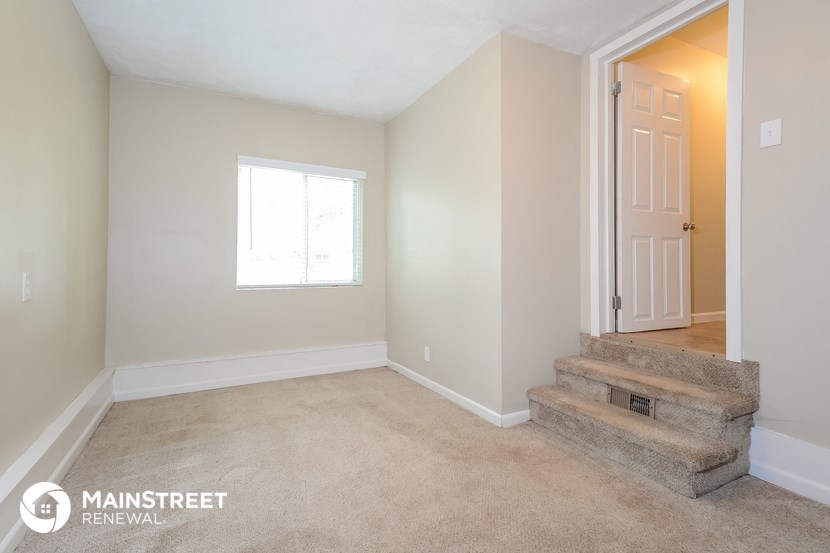 a living room with carpeted stairs and a white door