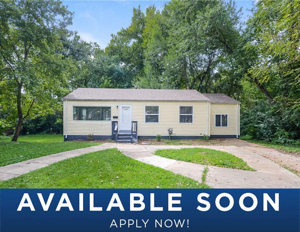 a small yellow house with a driveway and trees
