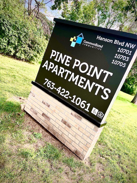 a sign for pine point apartments is in the grass