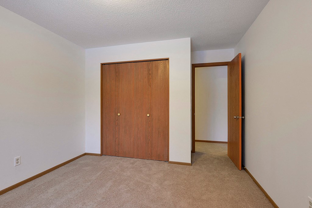 a bedroom with a door to a closet and a carpeted floor